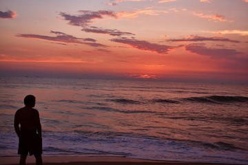Fototapeta premium a man watching a colorful sunset in the beach of goa