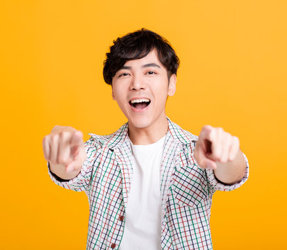 Portrait Of  Smiling Young Man Pointing Finger At Camera