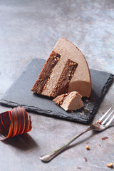 Contemporary Chocolate Hazelnut Dome Mousse Cake, covered with chocolate velvet spray and chocolate gourmet glaze, decorated with chocolate elements, on grey background.