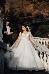 Wedding in a beautiful location. Wedding couple, bride and groom posing on the stairs. Elegant wedding dress. Bride, fashion model jewelry and beauty face, gorgeous  female