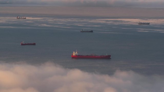 Fishing boats in the early morning at sunrise are in the port in a thick fog