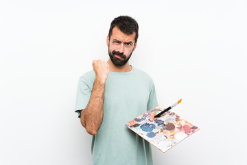 Young artist man holding a palette over isolated background with angry gesture