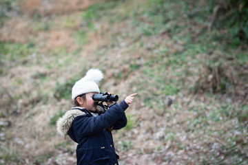 双眼鏡で遠くを見る少女