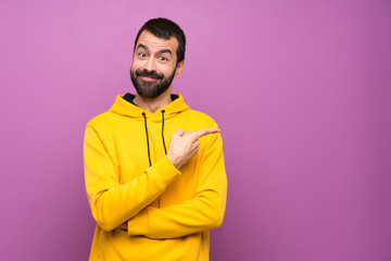 Handsome man with yellow sweatshirt pointing finger to the side