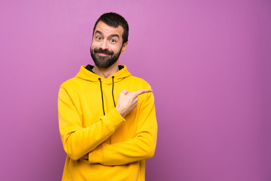 Handsome Man With Yellow Sweatshirt Pointing Finger To The Side