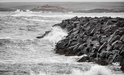 waves of the atlantic ocean breaking in stones in iceland in cold windy weather