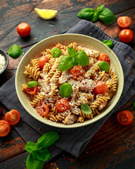 Healthy Chicken, fusilli pasta with tomatoes, basil and parmesan cheese. on wooden table.
