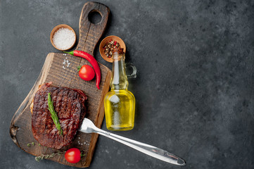 Grilled beef steak on a fork on a cutting board with spices with copy space for your text.