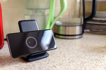 smartphone wireless charging on charging stand on kitchen tabletop