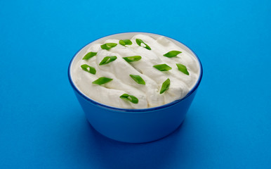 Bowl of sour cream on blue background
