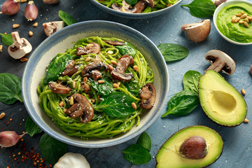 Vegan garlic mushroom pasta with spinach and avocado pesto drizzled with sesame seeds and roasted pine nuts