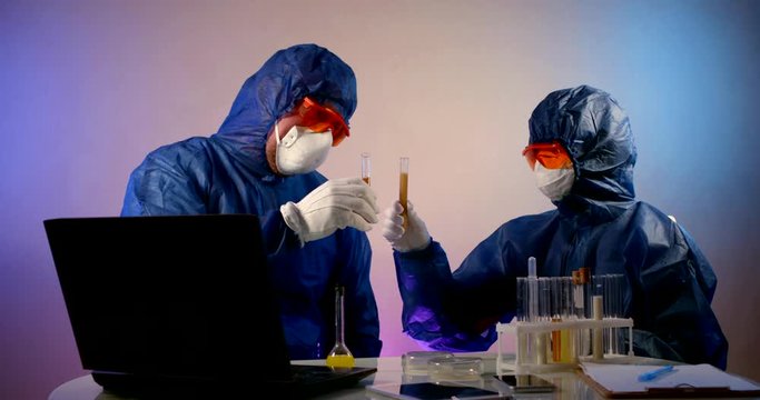 two funny scientists are clinking by test vials with virus like wine glasses in lab jokingly
