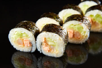 Traditional sushi roll with salmon, cream cheese, shrimp and cucumber on black stone. Japanese food