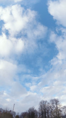 Fototapeta premium Bright blue sky with white clouds. Great background with copyspace. Winter and snow landscape. Stock photo.