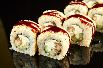 Traditional sushi roll with smoked eel, cream cheese and cucumber on black stone. Japanese food