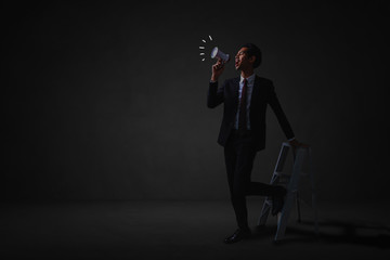 Fototapeta premium businessman standing and announce with megaphone to public relations in dark room