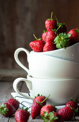 Fresh strawberry in white ceramic cup on wood table with nature light for food issue.