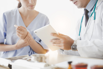 Doctor discuss records to patient by using digital tablet. Patient having consultation with Doctor...