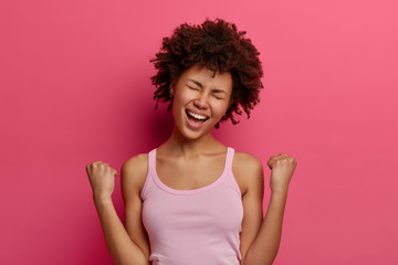 Photo of lucky overjoyed woman winner rejoices triumph at work, happy to recieve high profits,...