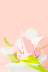 Flower banner. Close up composition of pink Origami paper tulip with green decorations in white box-heart on pink background