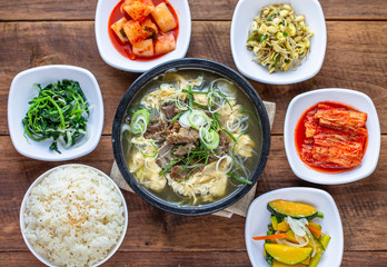 One big set of galbitang, korean style beef soup, serve with many slide dish and rice on wood table with nature light. For food issue.