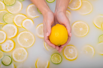 ripe lime in the hands of a woman. Top view Girl takes a milk bath with lemons. Citrus spa.
