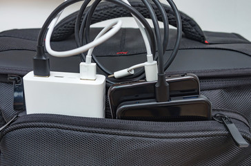 Smartphones charging from power bank in the pocket of travel bag. Selective focus. 