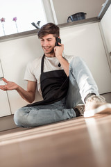 happy young man talking on mobile phone sitting on floor