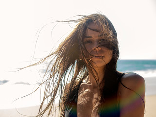 Portrait of a young woman with tangled hair from the wind against the background of the ocean