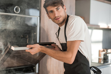 frustrated young man standing near broken oven