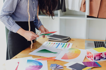 Young asian woman fashion designer working on her designs in the studio.