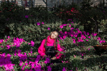 horizontal photo of a young girl in a bright sweater surrounded by blooming azaleas