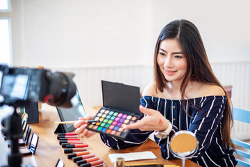 Asian woman blogger blogger with makeup cosmetics recording video clip online.