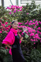 vertical portrait of a beautiful young girl in a flowering botanical garden