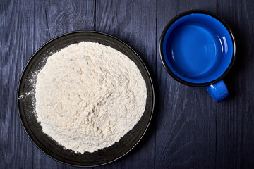 Plate with flour on a dark background.