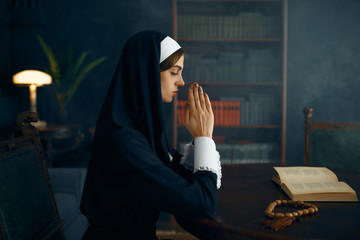 Young nun in a cassock prays crossed her arms