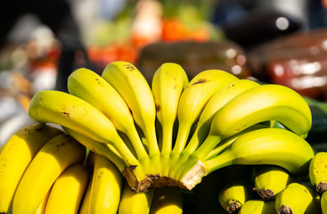 Plátanos apilados en un mercado y con desenfoque, con la luz del sol y un aspecto saludable
