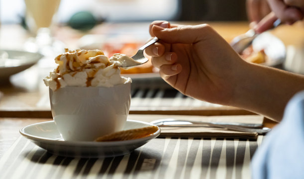 chica joven tomando un caf&eacute; con nata montada en un resturante con luz natural