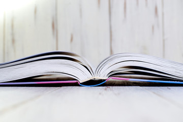 Opened book on a light wooden background.