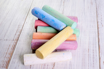 Multicolored chalk for drawing on a light wooden background. The concept of children's creativity.