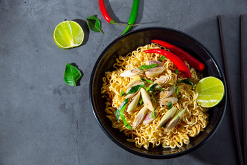 Spicy tom yum noodle dish, black bowl sprinkled with vegetables cooked with spices