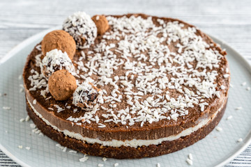 chocolate cake on a plate. Chocolate and coconut cake on a white wooden background. Foodfoto in a high key. Raw dessert