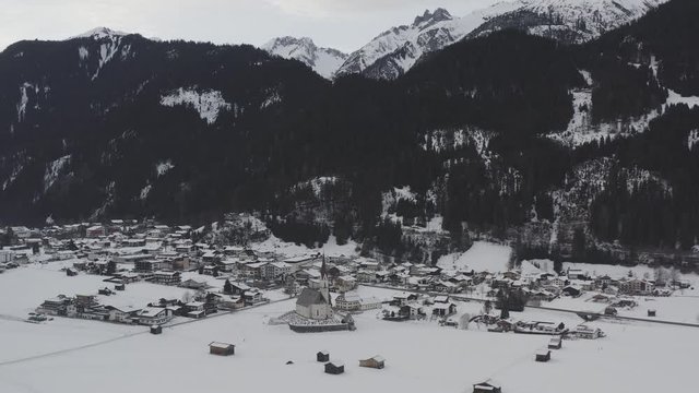 aerial view flying forward and downward into the village elbigenalp in austria with nice church and driven cars through the village