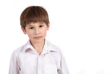 Portrait of a seven year old boy on a white background. Primary school student. Beautiful child in a white shirt .