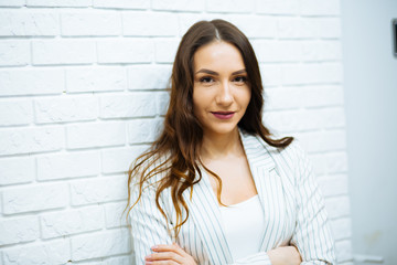 beautiful young business woman brown-haired in white clothes with a clear look near the white stone wall © ostap_davydiak