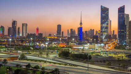 Fototapeta na wymiar Skyline with Skyscrapers day to night timelapse in Kuwait City downtown illuminated at dusk. Kuwait City, Middle East
