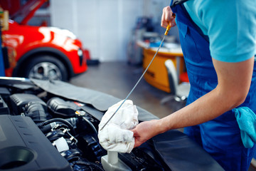 Worker checks the engine oil level, car service