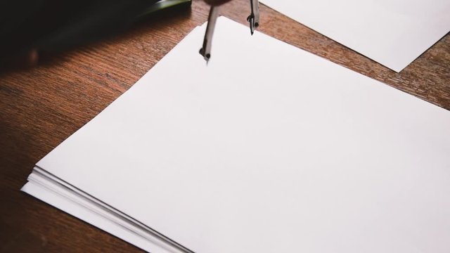 male hand draws an even circle on a paper sheet with a drawing compas