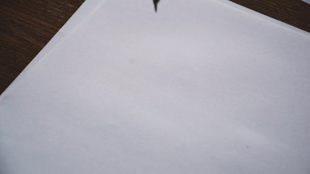male hand draws an even circle on a paper sheet with a drawing compas