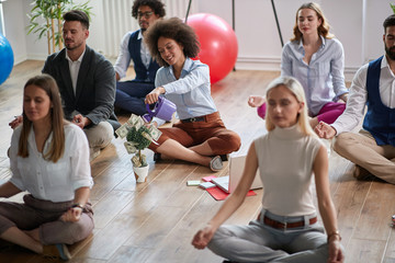 group of business colleagues  meditating at work, sitting on the floor, one female making visualization of money income increase.  business, meditation, visualization  concept